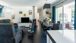 A modern living room with a flat-screen TV, sofa, and dining area with a table and chairs. - Villa in Vidauban near Sainte Maxime Beach (Vidauban)