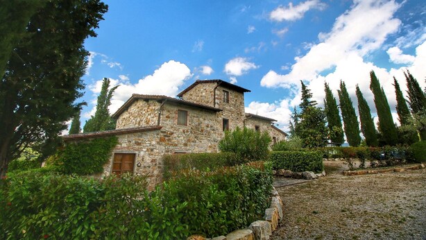 A stone building with a sloped roof, surrounded by greenery and tall trees. - Escape to Vineyards, Elba (Radda in Chianti)