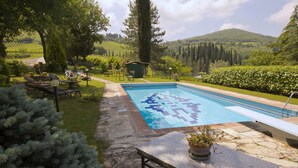 A swimming pool with a tiled deck, surrounded by greenery and a view of rolling hills. - Escape to Vineyards, Elba (Radda in Chianti)