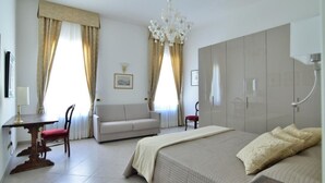 A hotel room with a bed, a sofa, a desk, and a wardrobe. - Sissi Suite (Venice)