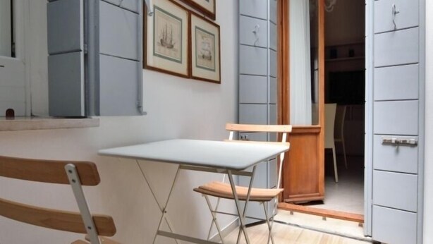 A room with a wooden bench, a white table, and a door leading to another room. - Sissi Suite (Venice)