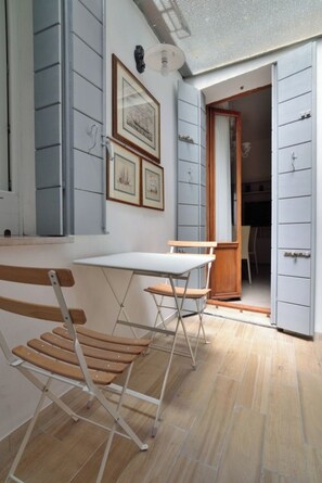 Una habitación con un banco de madera, una mesa blanca y una puerta que da a otra estancia.