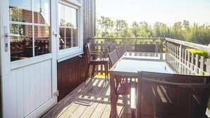 Una terraza con mesa y sillas, que da a una valla de madera y follaje.