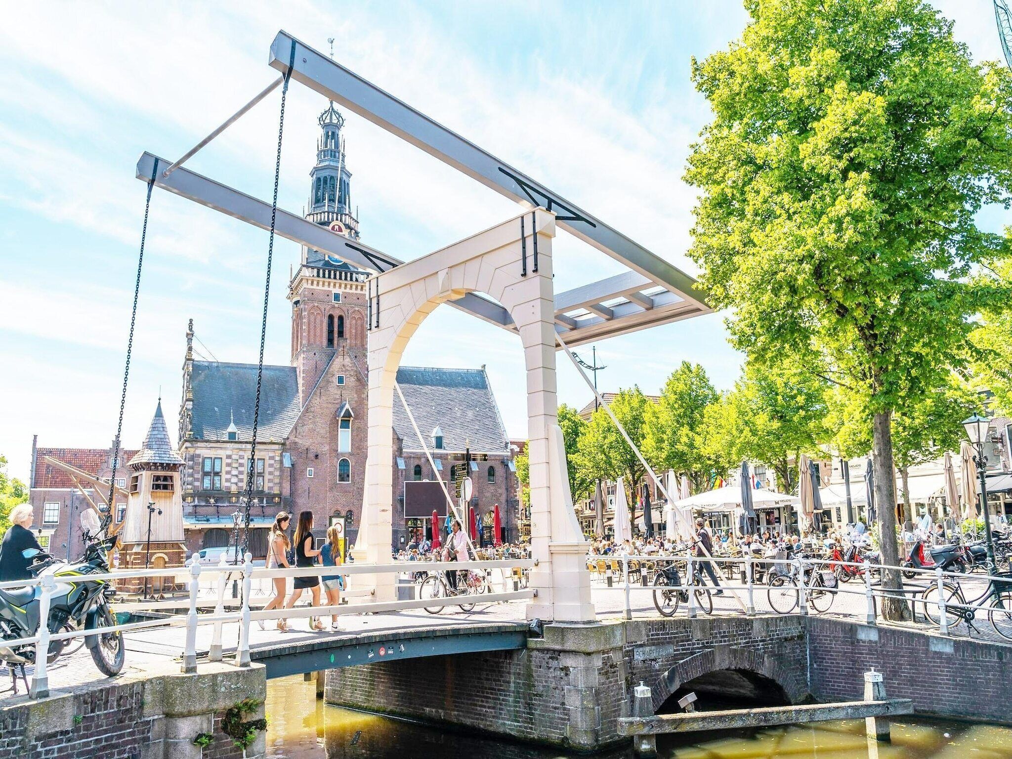 Un puente con estructura metálica, un edificio histórico con una torre y un canal con barcos.
