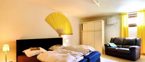 Habitación de hotel con cama, ventilador, sofá y armario.