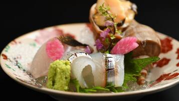 A plate with various seafood items, including fish and possibly shrimp, garnished with herbs and flowers.