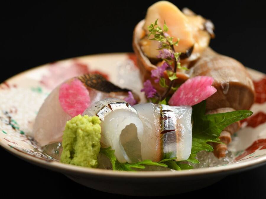 A plate with various seafood items, including fish and possibly shrimp, garnished with herbs and flowers.