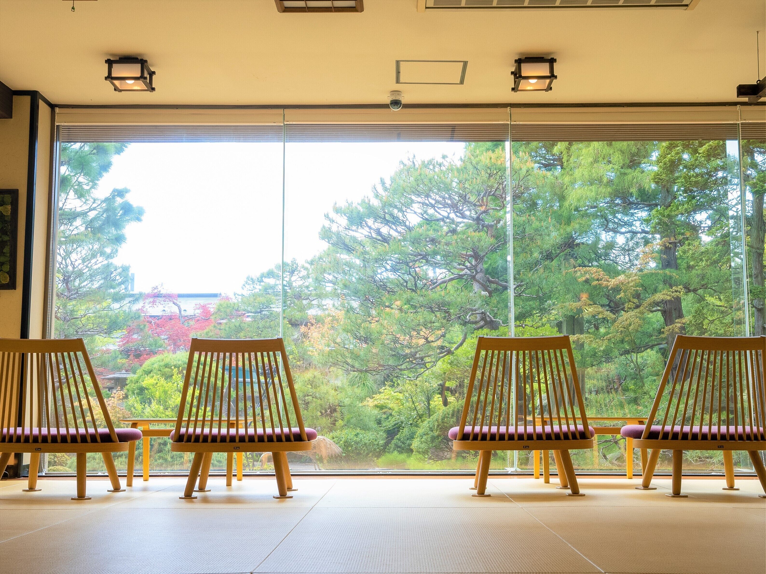 Ein Zimmer mit Tatami-Böden und drei Holzstühlen mit Kissen.