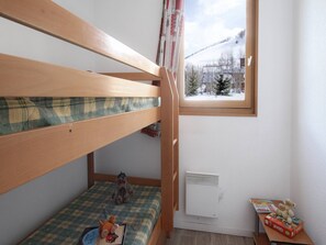 A bunk bed room with a window, a radiator, and toys on the floor.