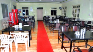 Un comedor con mesas y sillas, una alfombra roja y una máquina expendedora de Coca-Cola.