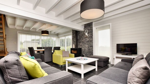 A modern living room with a fireplace, grey sofas, a coffee table, and a TV. - Holiday home suitable for families with sauna (Wilogne)