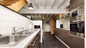 A modern kitchen with stainless steel appliances, a double sink, and a wooden staircase. - Holiday home suitable for families with sauna (Wilogne)