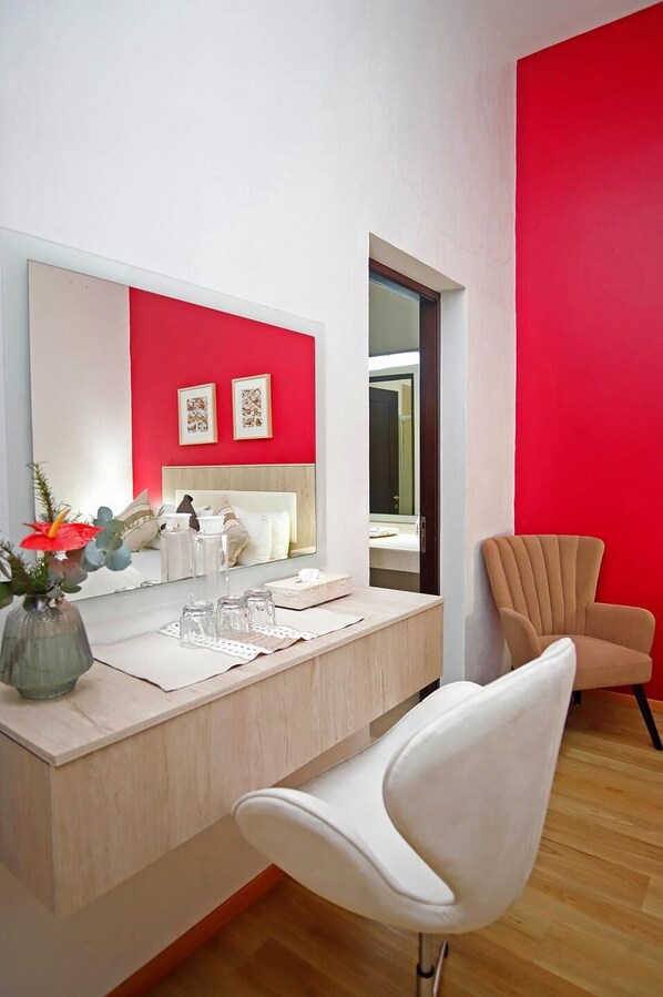 A modern bathroom with a white vanity, a large mirror, and a red accent wall. - Catrina de Alcala (Oaxaca)