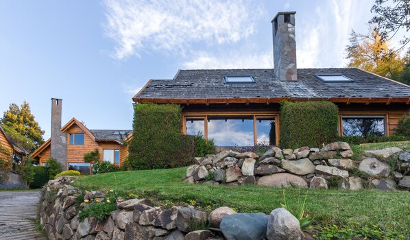 Una casa moderna con chimenea de piedra, ventanas amplias y un muro de piedra.