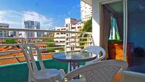 A balcony with a round table and two white chairs, overlooking a cityscape with buildings and a clear sky. - Apartamentos Suiteline Plus - Cerca al Mar (Santa Marta)