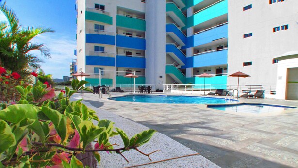 A pool area with a clear view of the surrounding buildings, including a multi-story structure with balconies. - Apartamentos Suiteline Plus - Cerca al Mar (Santa Marta)