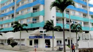 A multi-story hotel with balconies, a central column, and palm trees in front. - Apartamento Mar Azul - Smr143a (Santa Marta)