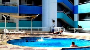 A swimming pool with a checkered floor, lounge chairs, and a covered seating area. - Apartamento Mar Azul - Smr143a (Santa Marta)