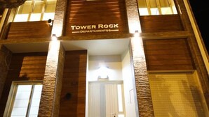 The exterior of Tower Rock Departmental with a prominent entrance and illuminated signage. - Tower Rock Departamentos Estándar (Puerto Deseado)