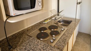 A kitchen with a microwave, stove, sink, and a refrigerator. - Tower Rock Departamentos Estándar (Puerto Deseado)
