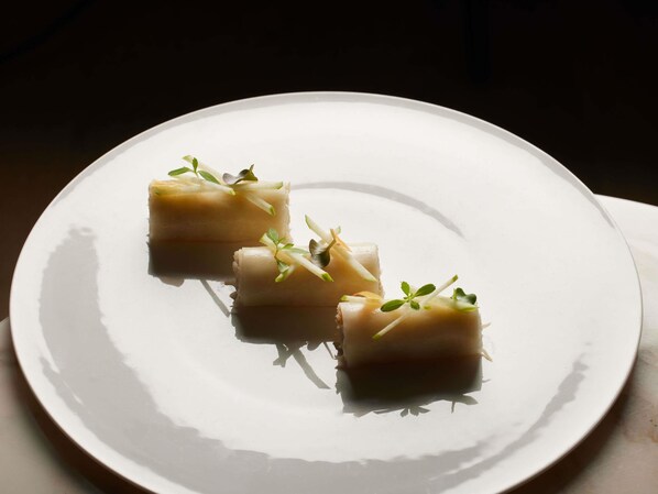 A white plate with three square-shaped food items, each garnished with green herbs, on a dark background. - 5 Terres Hotel & Spa - MGallery Collection (Barr)