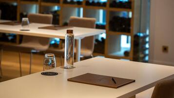 A conference room with a white table, a glass bottle, a glass, and a notebook.