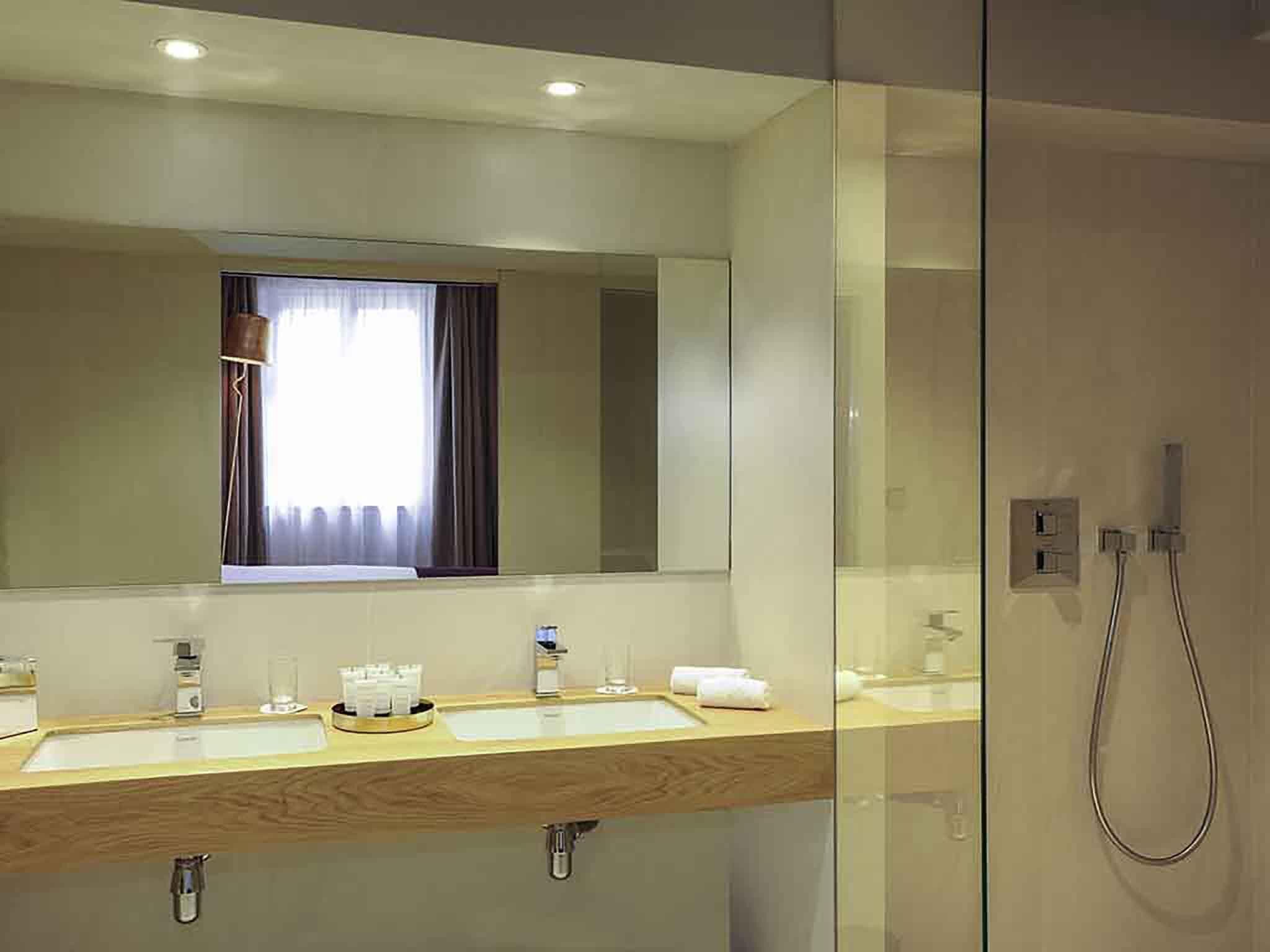 A modern bathroom with a glass shower enclosure, a large mirror, and a vanity with two sinks.