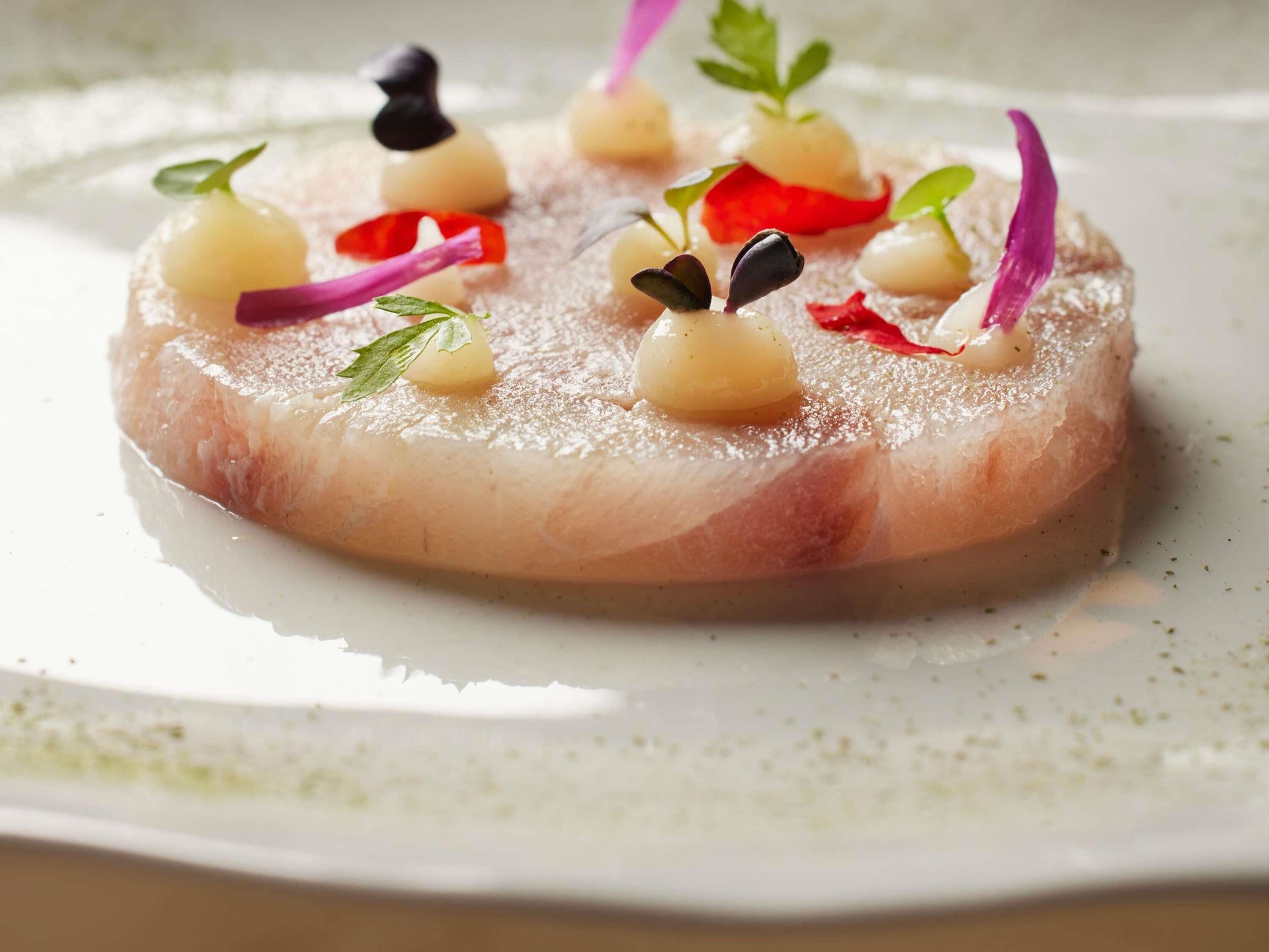 Un plat composé d’une base ronde et plate, garni de petites décorations et nappé d’une sauce.