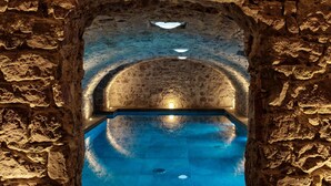 Una estructura de piedra en arco con una piscina en su interior.
