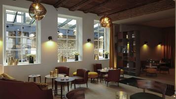 A modern interior with wooden beams, large windows, and a mix of seating arrangements.