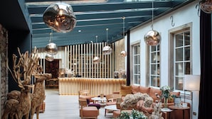 Un interior moderno con una recepción, zona de estar y elementos decorativos como esculturas de madera y jarrones.