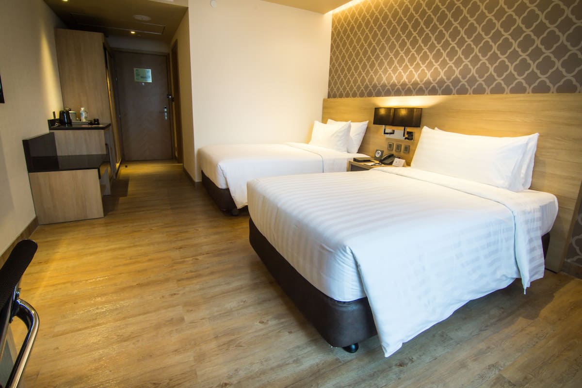 A hotel room with two beds, a desk, and a chair.