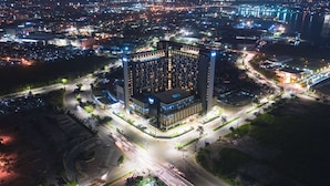 A high-rise building with a modern architectural design, surrounded by a well-lit urban area at night. - bai Hotel Cebu (Mandaue)