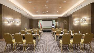 Una sala de conferencias con una mesa larga, varias sillas y una pantalla para presentaciones.