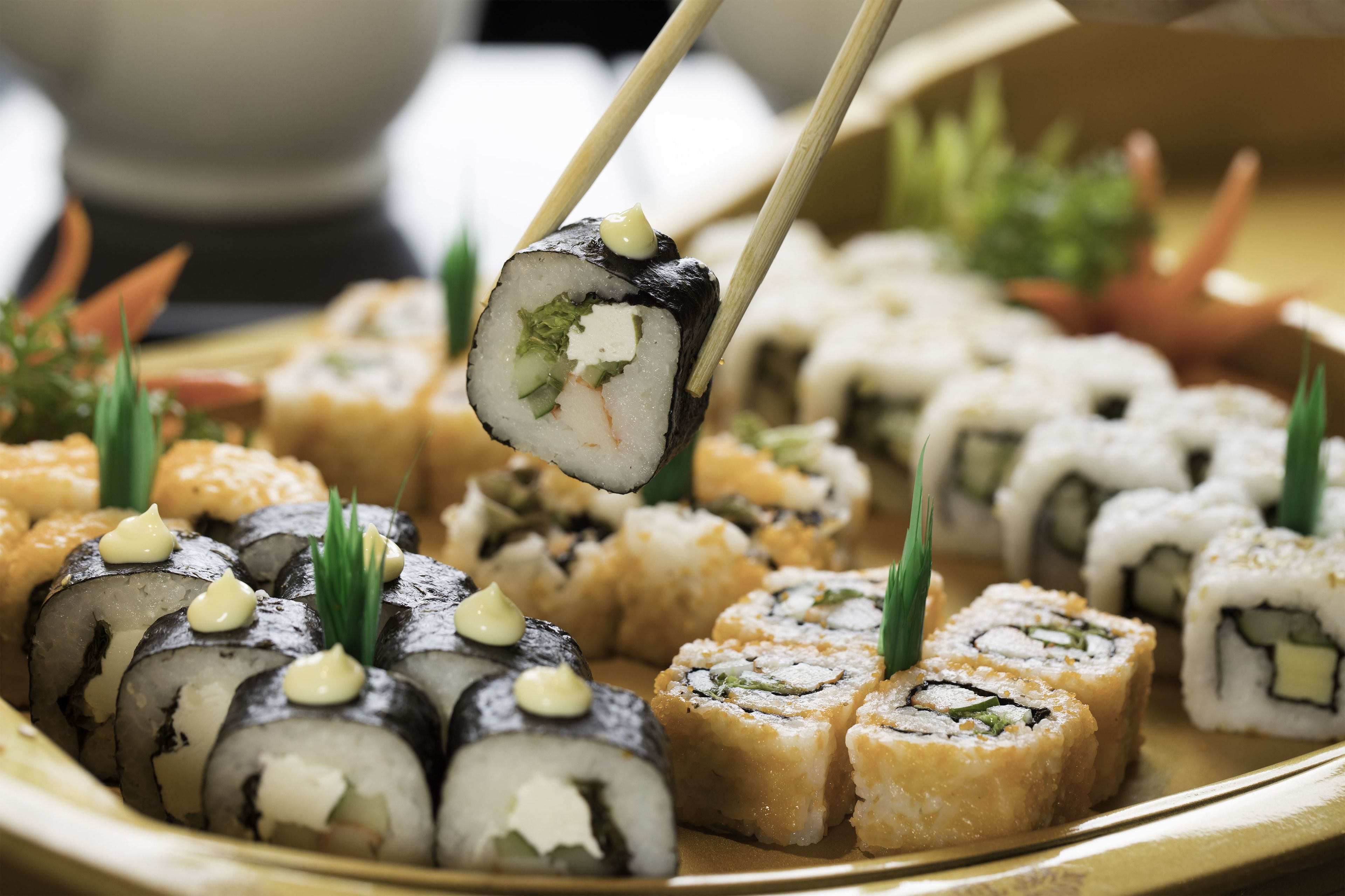 Variedad de rollos de sushi en una bandeja, algunos acompañados de wasabi y guarniciones.