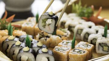 Variedad de rollos de sushi en una bandeja, algunos acompañados de wasabi y guarniciones.