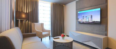 Una sala de estar moderna con un sofá, un sillón, una mesa de centro redonda y un televisor de pantalla plana montado en la pared.