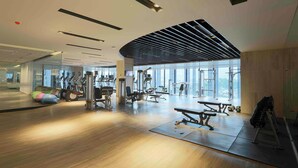 A spacious gym with various exercise equipment, large windows, and a wooden floor. - bai Hotel Cebu (Mandaue)