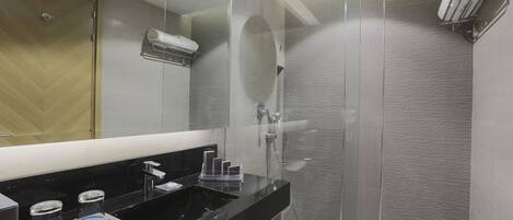 A modern bathroom with a black countertop, a glass shower enclosure, and a towel rack.