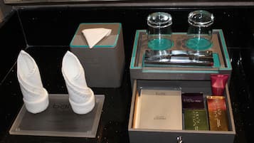 A hotel minibar with a tissue box, two glasses, and a selection of toiletries.