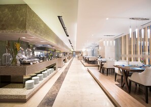 A modern hotel lobby with a long reception desk, seating area, and a clear view of the kitchen. - bai Hotel Cebu (Mandaue)