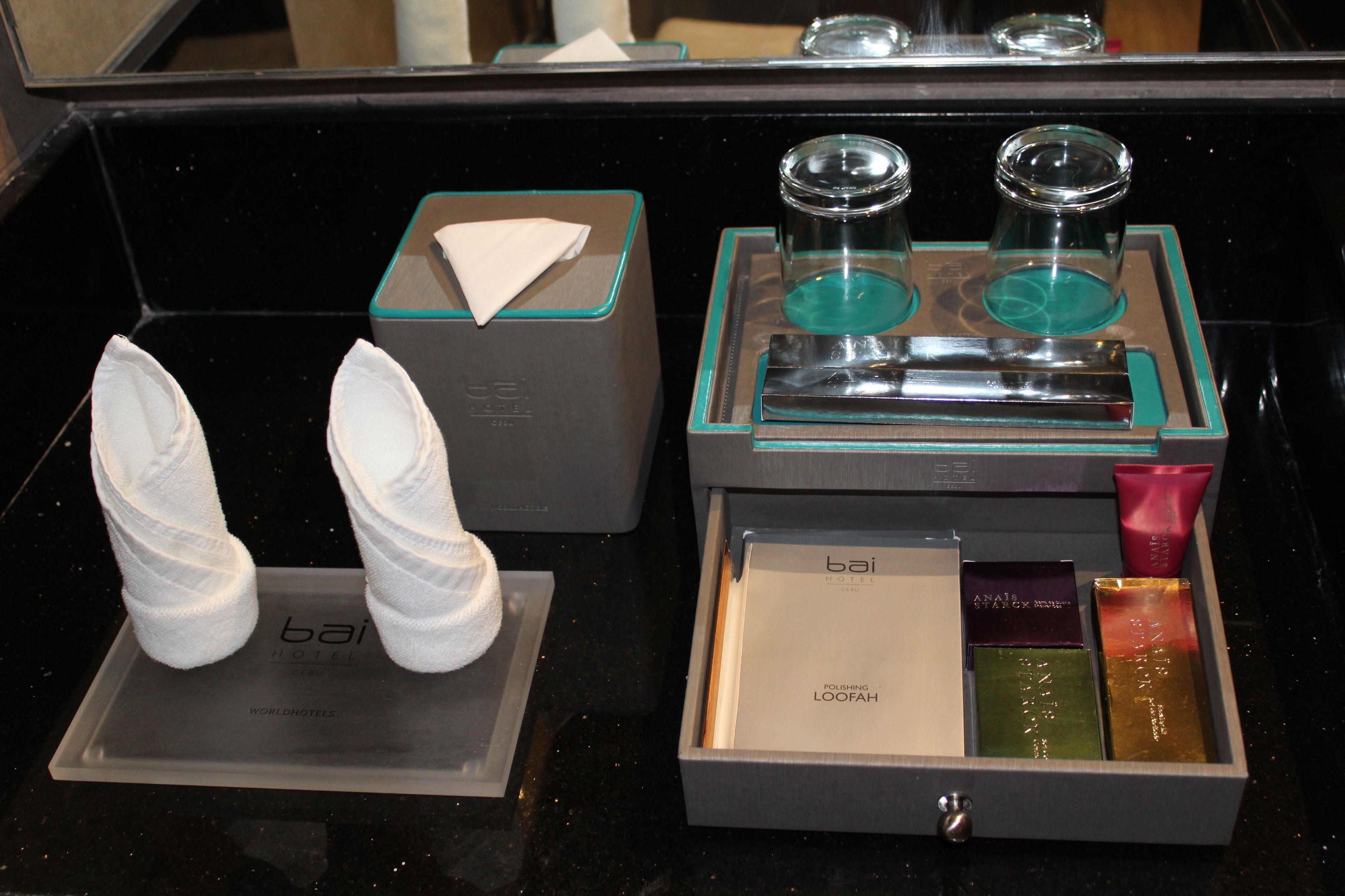 A hotel minibar with a tissue box, two glasses, and a selection of toiletries.