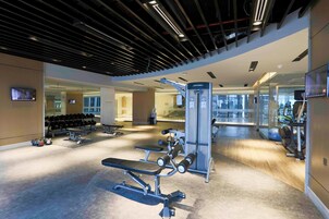 A modern gym with various exercise equipment, including benches and weight machines.