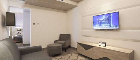 Una sala de estar moderna con un sofá, un reposapiés y un televisor montado en la pared.