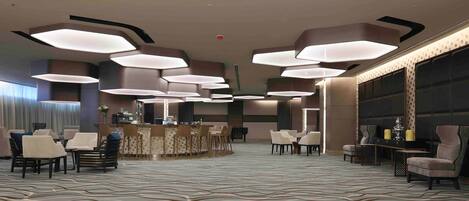A spacious lobby with modern lighting fixtures, a reception desk, and seating areas.