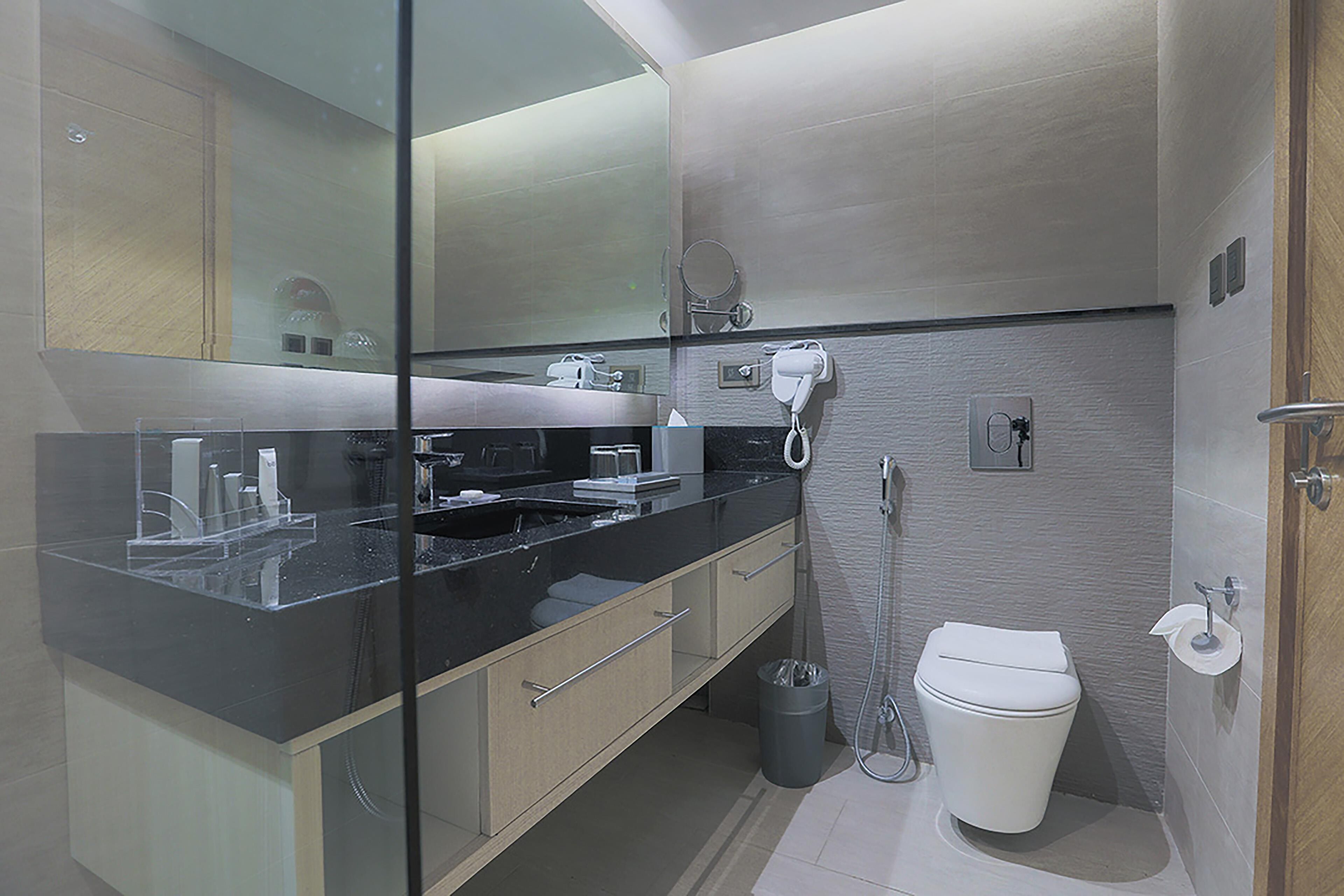 A modern bathroom with a glass shower enclosure, a black countertop, and a white toilet.