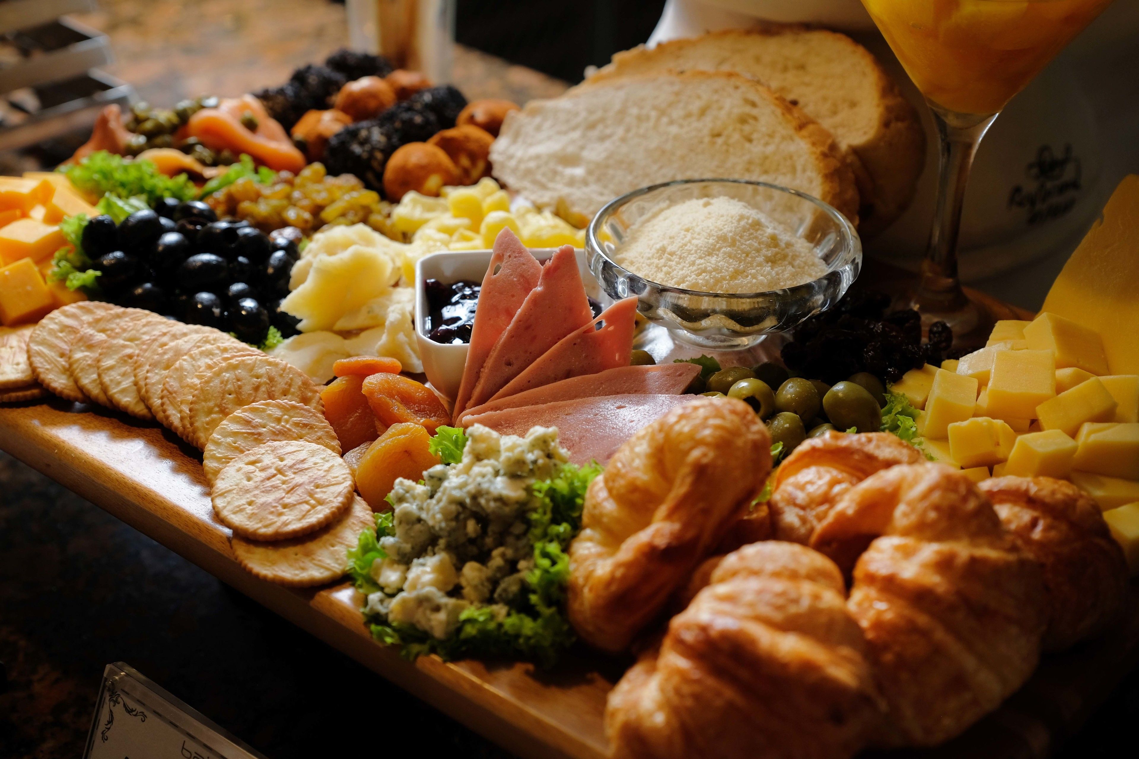 A charcuterie board with various cheeses, meats, crackers, and fruits.
