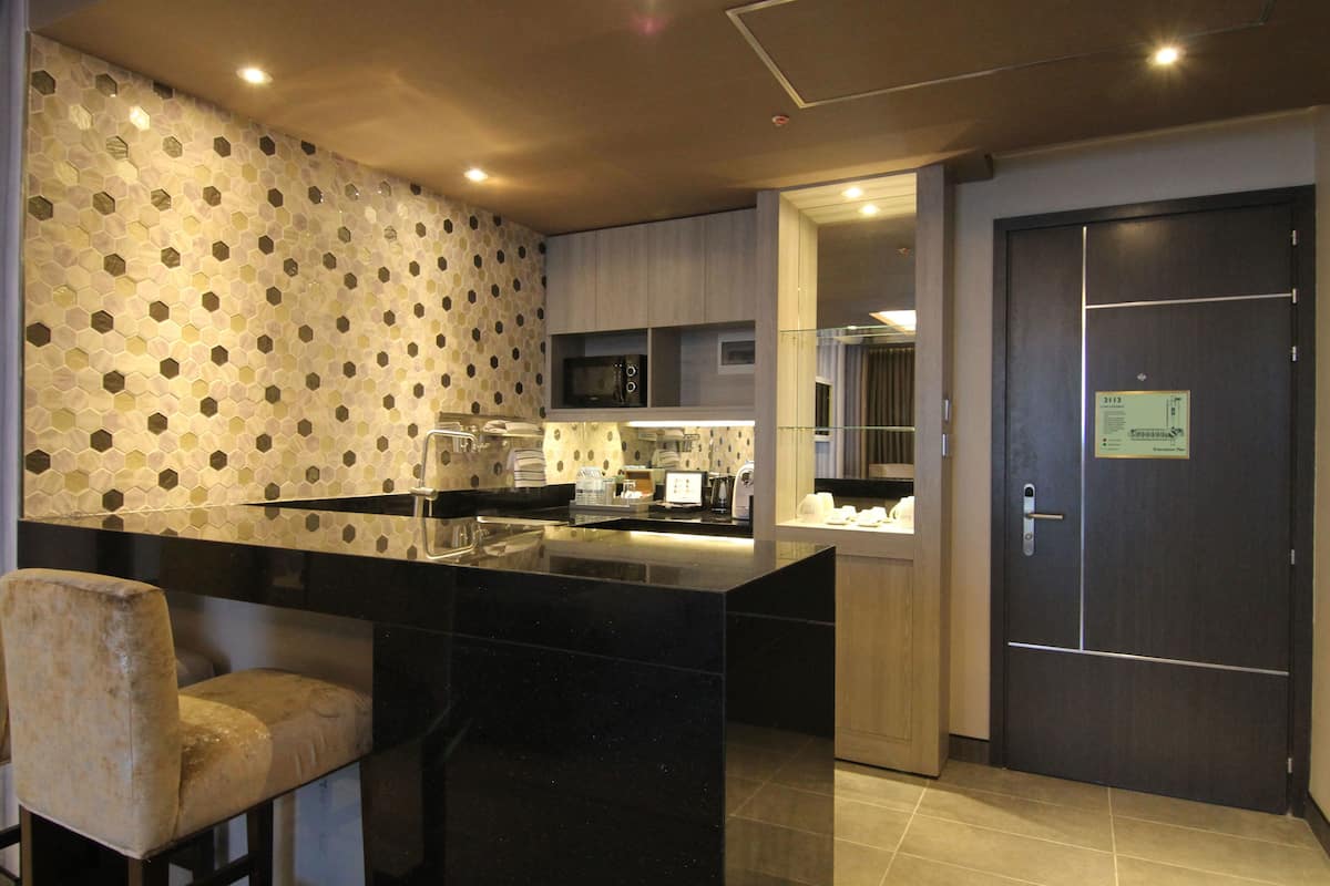 A modern kitchen with a black marble island, a microwave, and a coffee machine. There is a door with a sign on it and a chair in the corner.