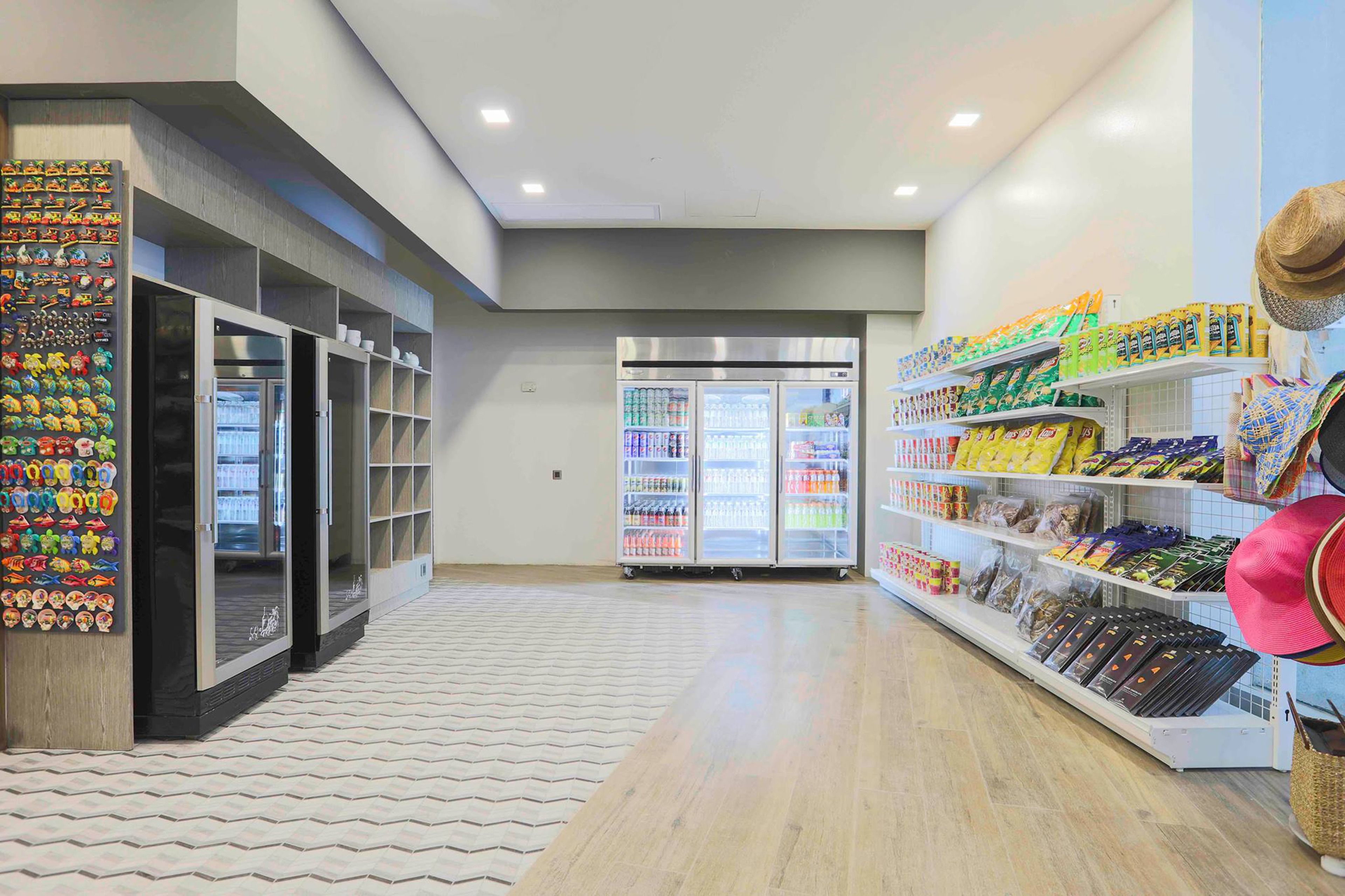 Ein sauberes, modernes Interieur mit gekühlten Auslagen, einem gemusterten Boden und Regalen voller Snacks und Hüte.