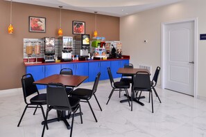 A restaurant with blue cabinets, black chairs, and a counter with various food and drink dispensers.